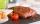 fettina di carne rossa su piatto nero con pomodoro